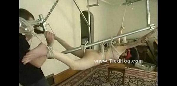  Blonde girl has her nipples bound in clamps while being tied up on a glass table